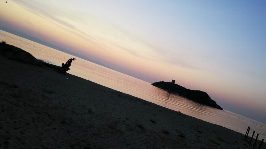 San Macario Islet seen from pula beach at sunset, Italy, Sardinia. Slow tilting aerial
