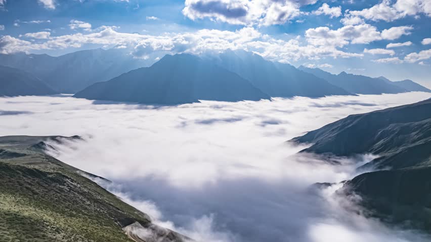 Dramatic time lapse view of Mount Gongga with sea of clouds flowing through valleys in Sichuan Province, China. Stunning backlighting creates ethereal mountain landscape.