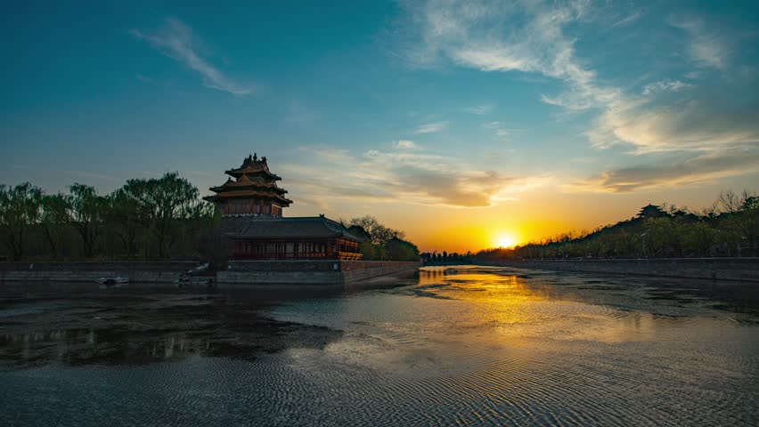 Beautiful sunset view of Forbidden City corner tower reflected in moat waters, Beijing China. Golden hour time lapse photography showcasing traditional Chinese architecture.