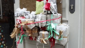 Colorful Christmas gifts wrapped in festive fabric with ribbons and bows tied together on a decorated door creating a cheerful holiday atmosphere outside the home - Powered by Shutterstock - Get 15% off with code: PIKWIZARD15