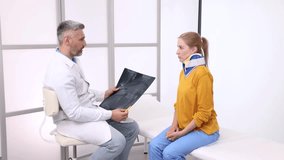 Orthopedist-traumatologist examines MRI images while female patient in neck brace sits attentively in medical office during check-up appointment - Powered by Shutterstock - Get 15% off with code: PIKWIZARD15