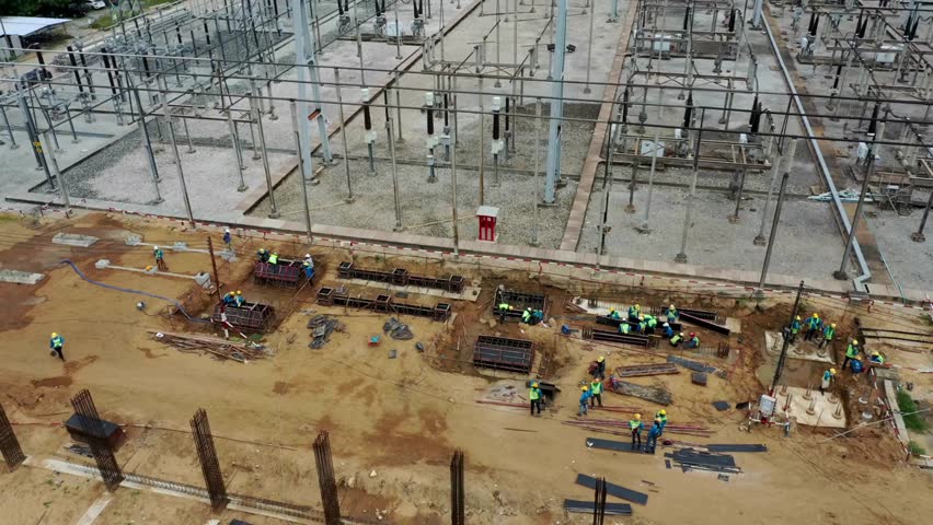 High angle view shows Workers constructing concrete forms for equipment foundations inside substation at daytime. Industrial scene with power infrastructure in progress. - Powered by Shutterstock - Get 15% off with code: PIKWIZARD15