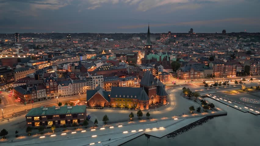 Flight over the evening city of Aarhus in Denmark. Aerial shot of vibrant city of Aarhus at night with stunning views of illuminated buildings and bustling street