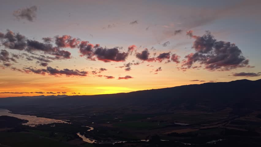 Cinematic panning aerial sunset footage creates warm and comforting atmosphere in captivating new zealand landscape in darkening valley with windy river