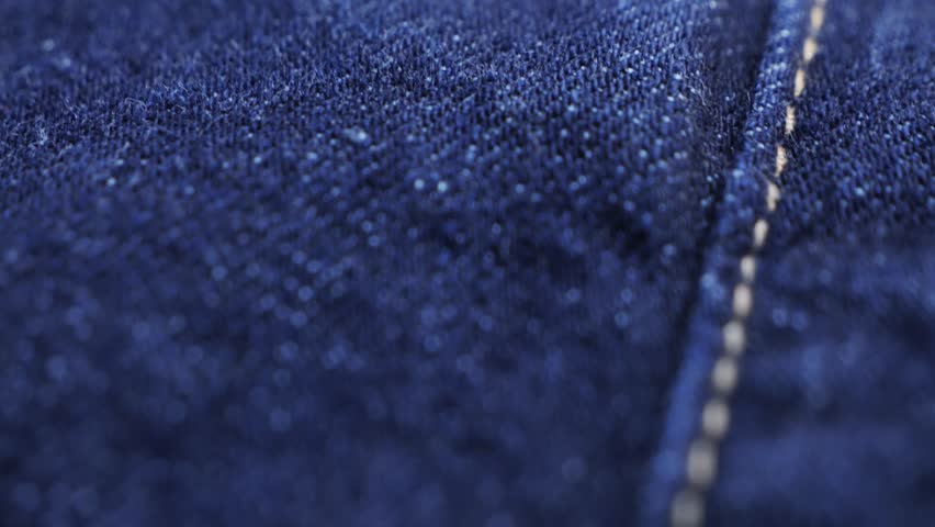 Close up of details and elements of jeans. Stitched seams. Texture of fabric blue denim. High quality 4k footage