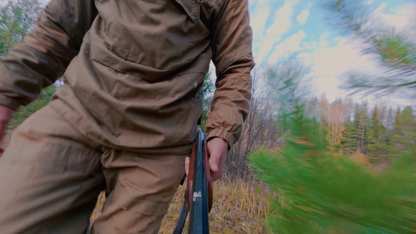 The hunter cautiously sneaks up to the target, shoots and runs recklessly towards the beast. A man on a hunting trip with a smoothbore rifle. Autumn hunting.