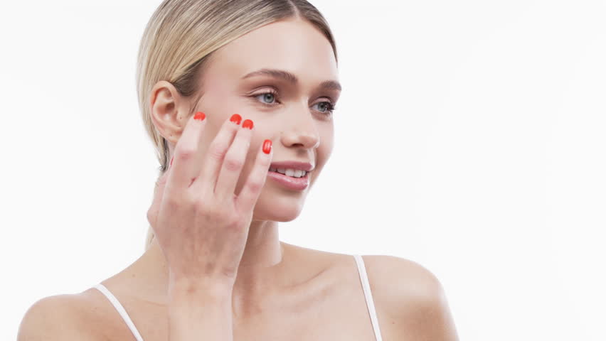 Beautiful woman with clear skin gently touching her face, showcasing a natural glow and healthy complexion, embodying the essence of modern cosmetology and skincare practices