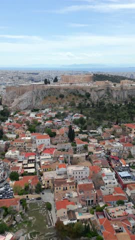 Aerial view of the Acropolis hill with the Parthenon temple above the colorful Plaka district in Athens, Greece. Beautiful contrast of ancient ruins and modern cityscape.
