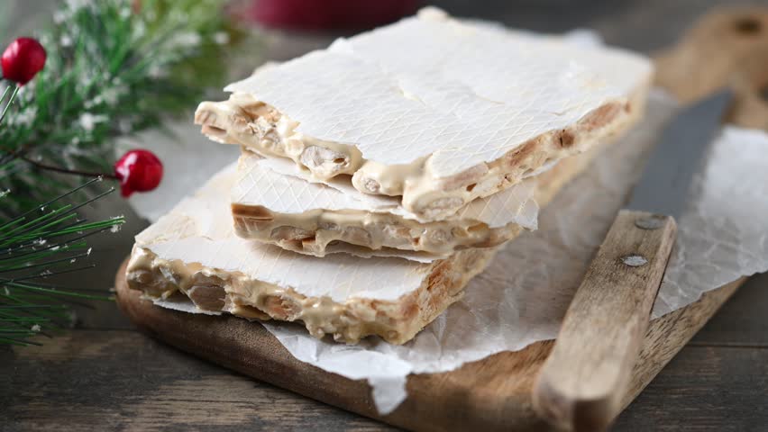 Delicious almond nougat on wooden table. Traditional Christmas sweet	