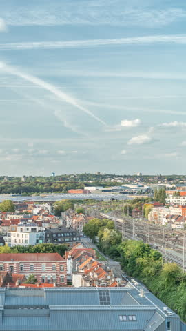 Aerial panorama of Laeken timelapse, Brussels Capital Region, Belgium, showcasing cityscape with red rooftops, railway tracks and trains arriving and departing. Historic charm and urban development