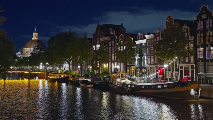 Amsterdam, Netherlands - 20.08.2025: Night view of Amsterdam cityscape with canal, bridge and medieval houses