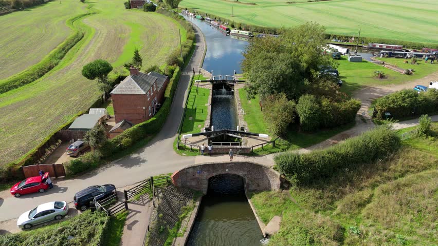 Aerial view of boats traversing the serene canal lock amid lush greenery, contrasting with the red brick building, Derby, England, United Kingdom.
