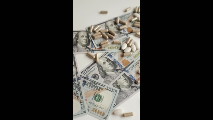 Dollar bills and various pills and capsules closeup video. Soft focus and natural light tablets, cinematic slow motion video of various medicine supplements and money. Expensive healthcare concept.