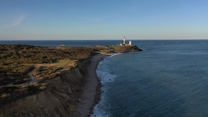 Aerial view of the iconic Montauk Point Lighthouse standing tall on the coast where the Atlantic meets the sky in vibrant hues, Montauk, New York, United States.