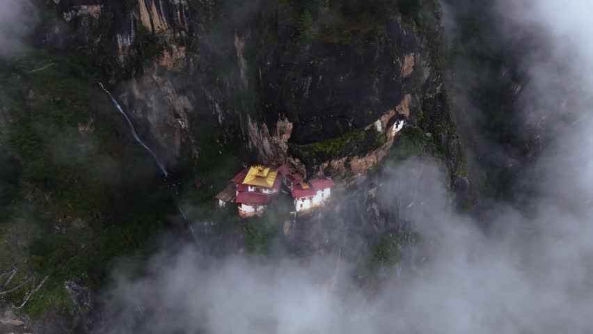 Aerial view of the iconic Tigers Nest monastery clinging to the cliffside, shrouded in mist, a testament to architectural marvel, Paro, Bhutan.