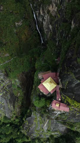Aerial view of the iconic Tigers Nest temple clinging dramatically to the cliffside amid lush greenery, a testament to faith and architectural wonder, Paro, Bhutan.