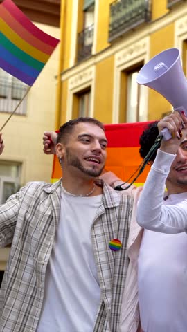 Diverse group of young people demonstrating for lgbtq rights, holding a rainbow flag and megaphone, laughing and shouting with joy during an outdoor pride parade on a city street