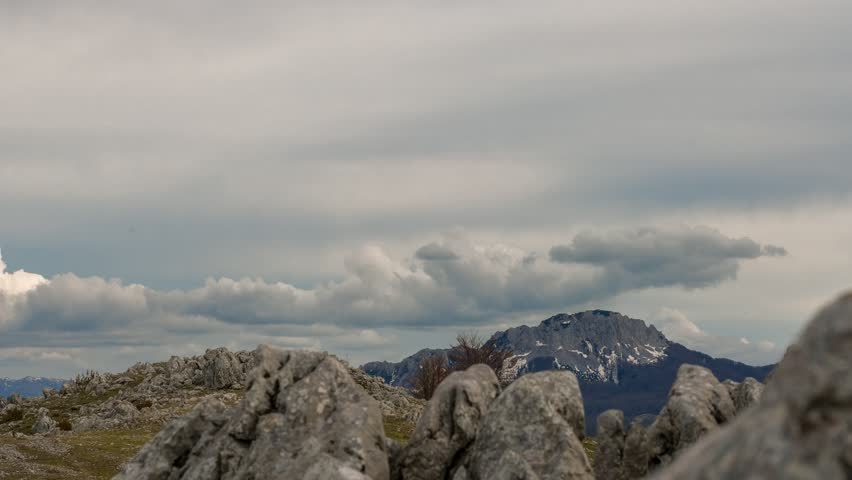 Time lapse of a cloudy sky above rocks and a mountain in the distance