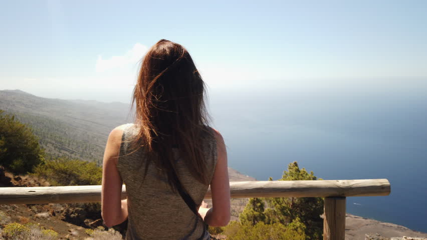 woman contemplating the vast ocean and coastline from a scenic viewpoint on El Hierro island
