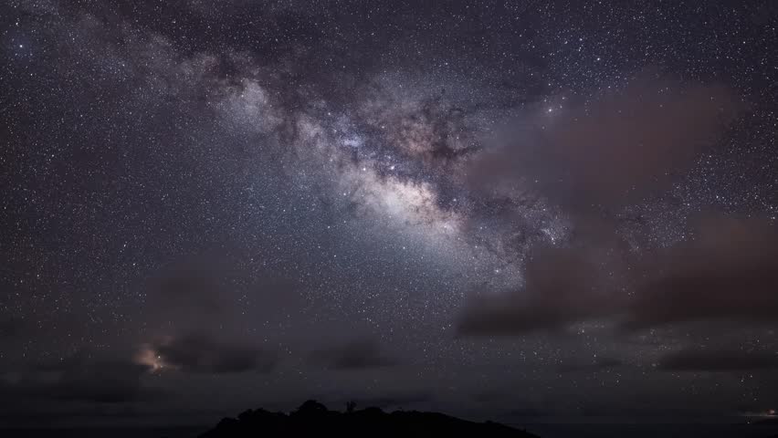 Stunning Milky Way galaxy stretching across starry night sky above mountain silhouette, perfect for astrophotography and time lapse projects.