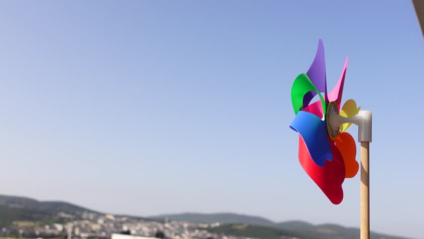 Colorful pinwheel spins against clear sky and distant landscape