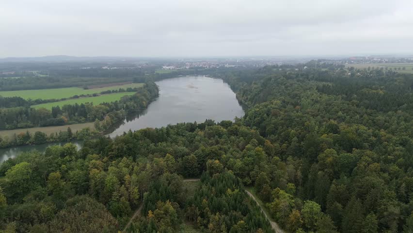 Aerial autumn view of the Lech River near Poering and Landsberg am Lech in Bavaria, Germany. Foggy morning over forests and wide riverbanks showcasing peaceful natural scenery.