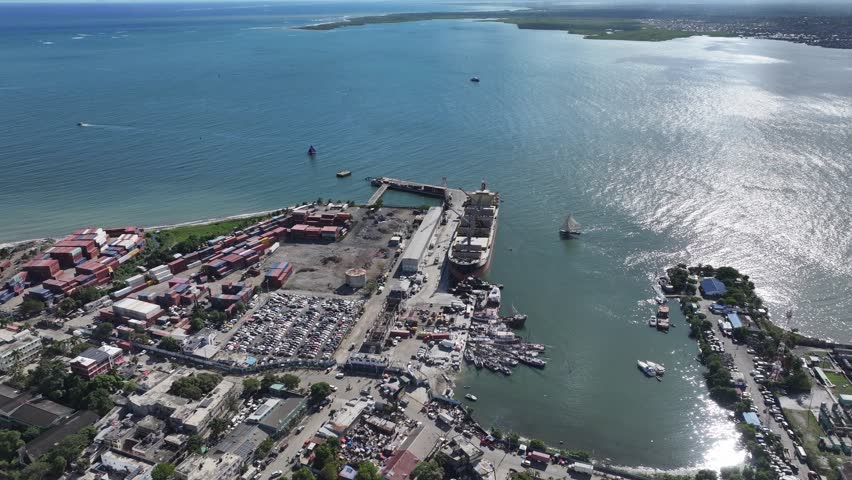 Cap-Haïtien port, cargo ship, shipping containers, junkyard, and fishing boats, industrial area in Haiti. Aerial drone