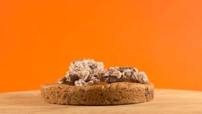 Close-up of a delicious cookie topped with caramel, cream, and sugared pecan, displayed on a rotating wooden plate with an orange background. - Powered by Shutterstock - Get 15% off with code: PIKWIZARD15