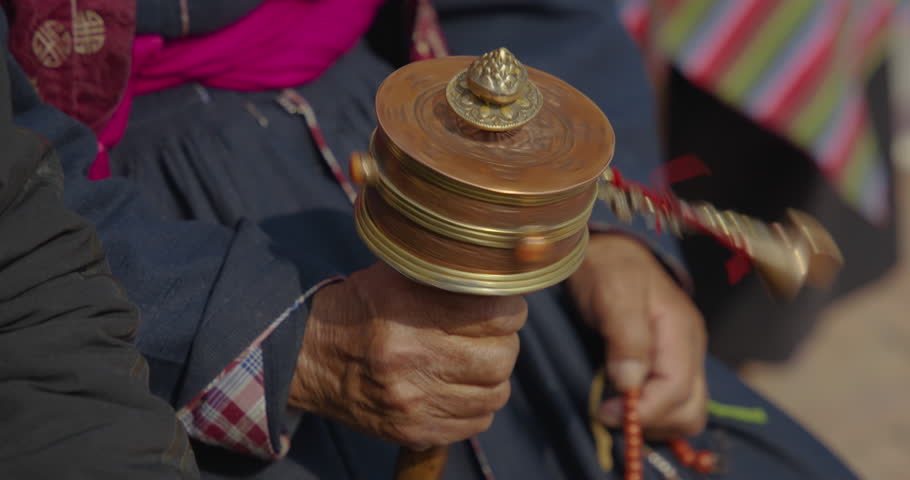 A monk meditates at Boudhanath stupa, Nepal, gently rotating a prayer wheel while counting beads. The rhythmic motion reflects Buddhist devotion, mindfulness, and peace in spiritual practice