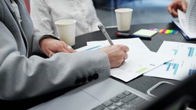 Businesspeople analyzing printed charts and bar graphs during meeting, close-up view of hands and documents - Powered by Shutterstock - Get 15% off with code: PIKWIZARD15