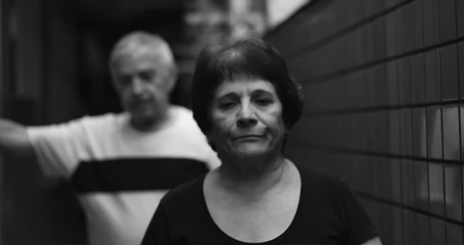 Elderly man defending his point during heated argument, woman gesturing emphatically, black and white scene of intense conflict and communication breakdown