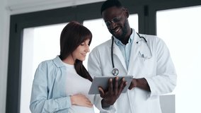 Video of cheerful gynecologist doctor showing to pregnant woman ultrasound scan baby with digital tablet in medical consultation - Powered by Shutterstock - Get 15% off with code: PIKWIZARD15