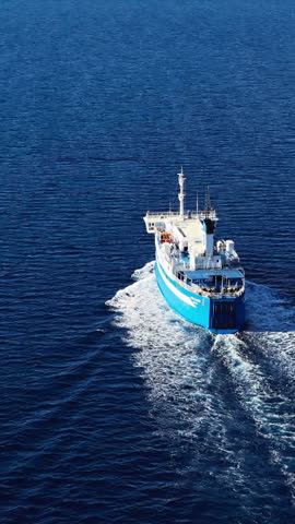 Ferry boat on open water cruising between Greek islands. Aerial view, vertical