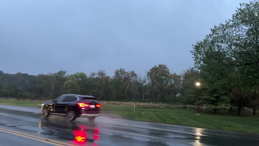 Exton, Pennsylvania - October 13th, 2025: Cars driving on a wet road on a cloudy rainy morning