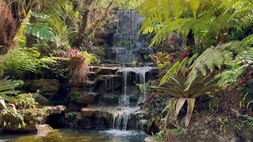 Artificial waterfall in the forest, Artificial waterfall flowing on cement rocks, Soft focus, Slow motion.	