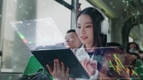 Asian woman wearing headphones sitting in bus. Holding tablet device with holographic stock charts above screen. Female analyzing financial data while commuting on public transport during daytime. - Powered by Shutterstock - Get 15% off with code: PIKWIZARD15