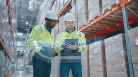 Two industrial workers in helmets and reflective jackets checking stock in warehouse. One holding tablet displaying digital projection while colleague pointing at shelves with packed goods. - Powered by Shutterstock - Get 15% off with code: PIKWIZARD15