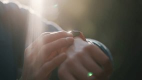 Closeup of a male athlete's hands using a smartwatch to track performance and heart rate during training in a park, with beautiful sunlight creating a lens flare in the background - Powered by Shutterstock - Get 15% off with code: PIKWIZARD15