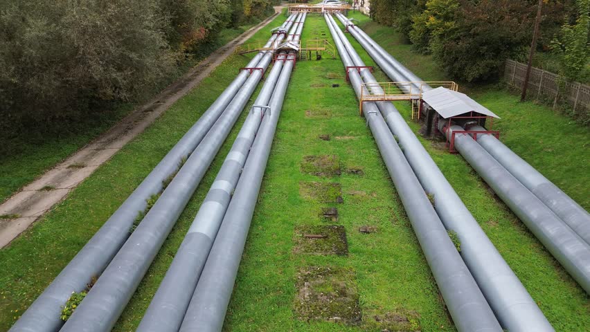 Expansive view of industrial pipes transporting gas and water, showcasing a gradual camera zoom out revealing the extensive network and surrounding greenery, emphasizing infrastructure development