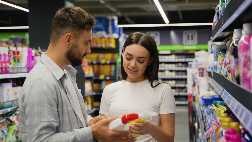 Young couple choosing household chemicals in supermarket aisle