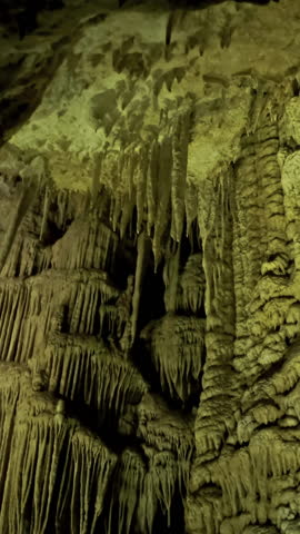 Beautiful cave with stalactites underground cavern in magic light, tilt view. Vertical video