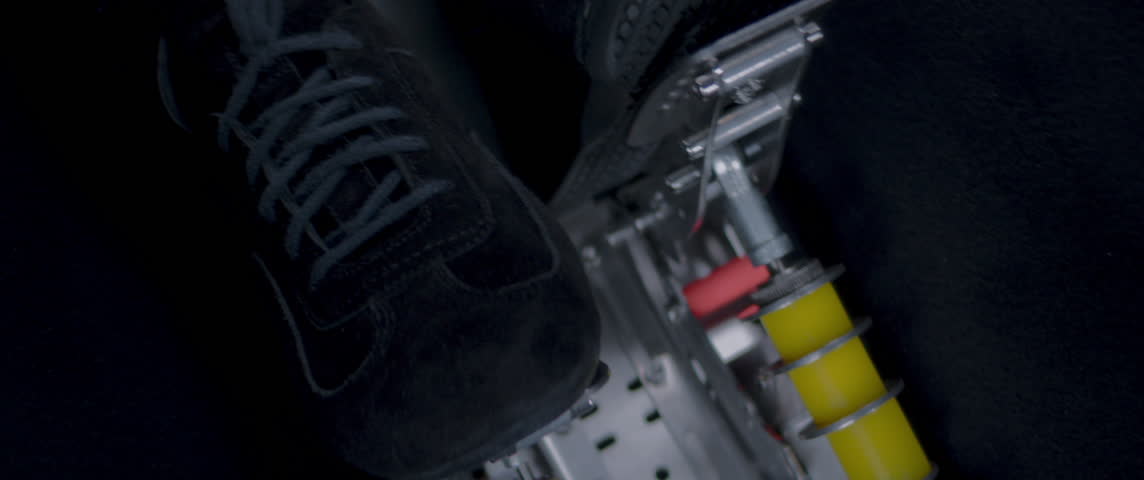 Close-up video of a race car drivers legs and feet engaging the pedals, accelerating under foot during high-speed driving