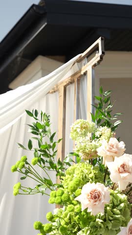 Colorful wedding romantic flower arch with white fabric. Summer atmosphere on the street. Green white and red flowers. Rose, hydrangea, anthurium, dahlia, chrysanthemum, amaranth, dianthus white spray