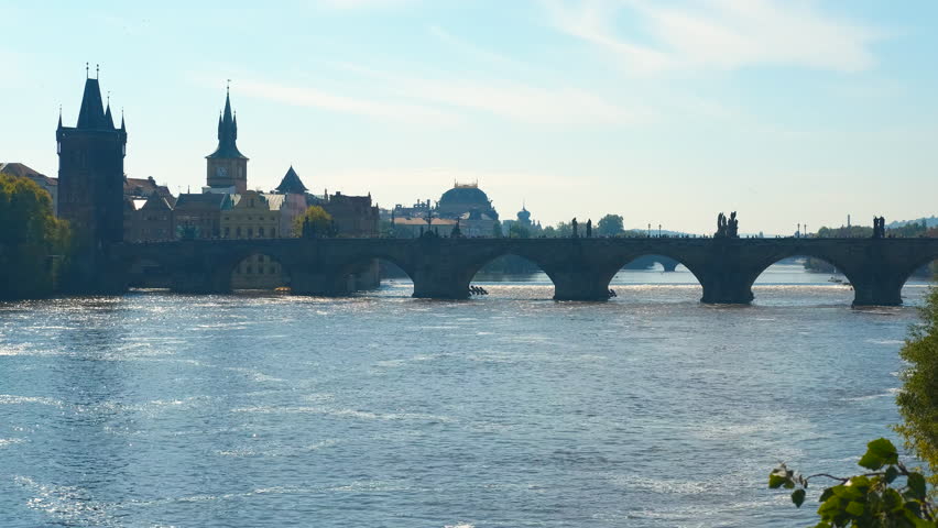 Charles bridge over vltava river with tourists walking in prague. Gentle waves lap against the supports of the charles bridge as tourists stroll across, the backdrop of prague