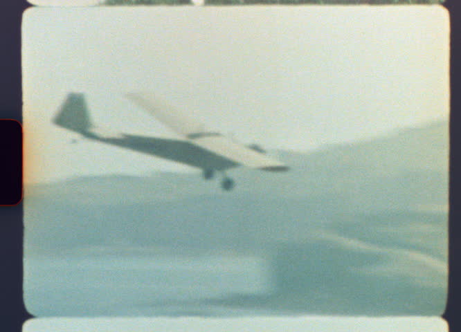 Original, Authentic 8mm film recording of a classic small airplane gracefully descending for landing over a populated area, capturing a nostalgic journey with genuine light leaks and film grain