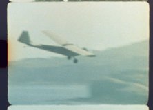 Original, Authentic 8mm film recording of a classic small airplane gracefully descending for landing over a populated area, capturing a nostalgic journey with genuine light leaks and film grain - Powered by Shutterstock - Get 15% off with code: PIKWIZARD15