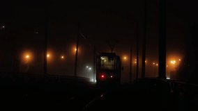 Tram at night in dense fog with glowing streetlights, mysterious city transport scene with dramatic lighting and dark atmosphere, urban loneliness and silence in moody cinematic style - Powered by Shutterstock - Get 15% off with code: PIKWIZARD15