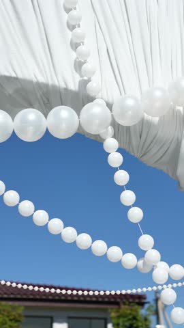Elegant wedding arch on the podium with fabric, beads, candles, tiers and romantic floral arrangement in white and green tones. Amaranth, anthurium, hydrangea, rose, dahlia. Summer windy atmosphere.