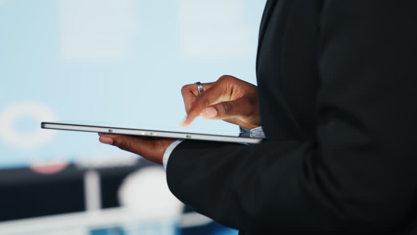 Close up of businesswoman using tablet to compare company KPIs data on digital videowall before making decisions. Entrepreneur analyzing key performance indicators using device app - Powered by Shutterstock - Get 15% off with code: PIKWIZARD15