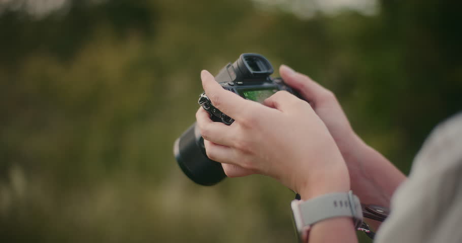 Close-up of a photographer reviewing shots and using a camera during an outdoor photo session.